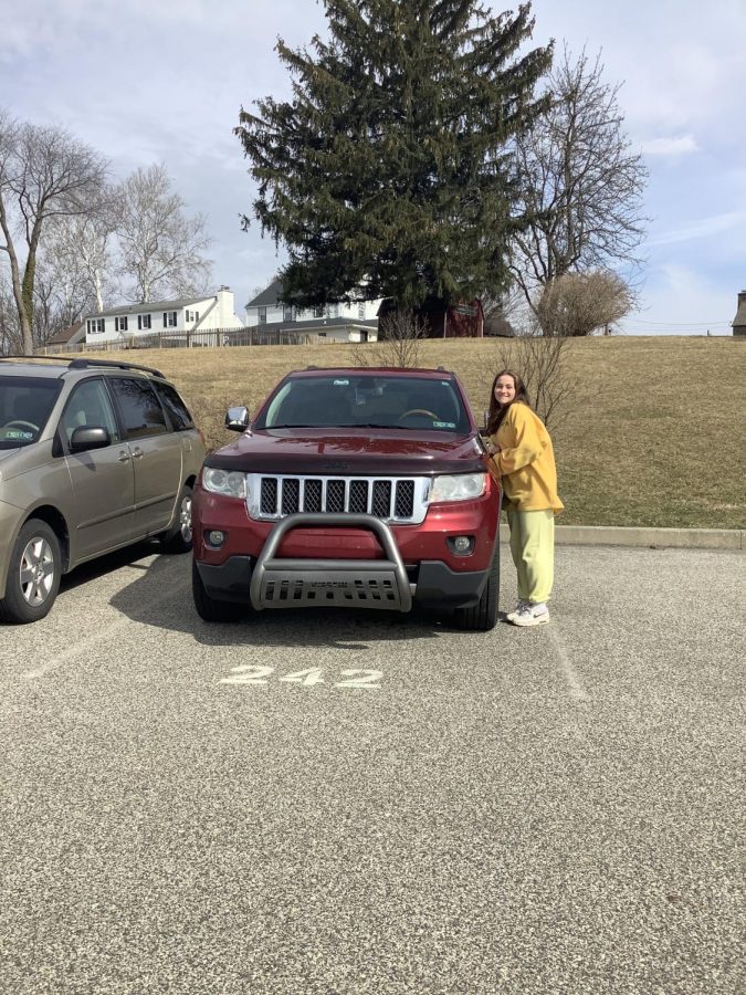 Kathryn Zampirri 23 steps outside to pose with her Jeep. Parked in the MSJA parking lot amongst many other Jeeps, the bright red hue to the car makes her car stick out. 