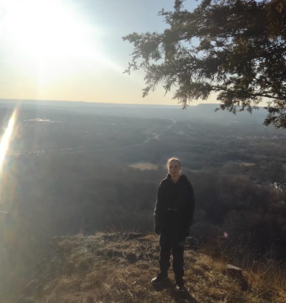 Kris stops and poses for a picture in front of a wonderful view of the land below him. 