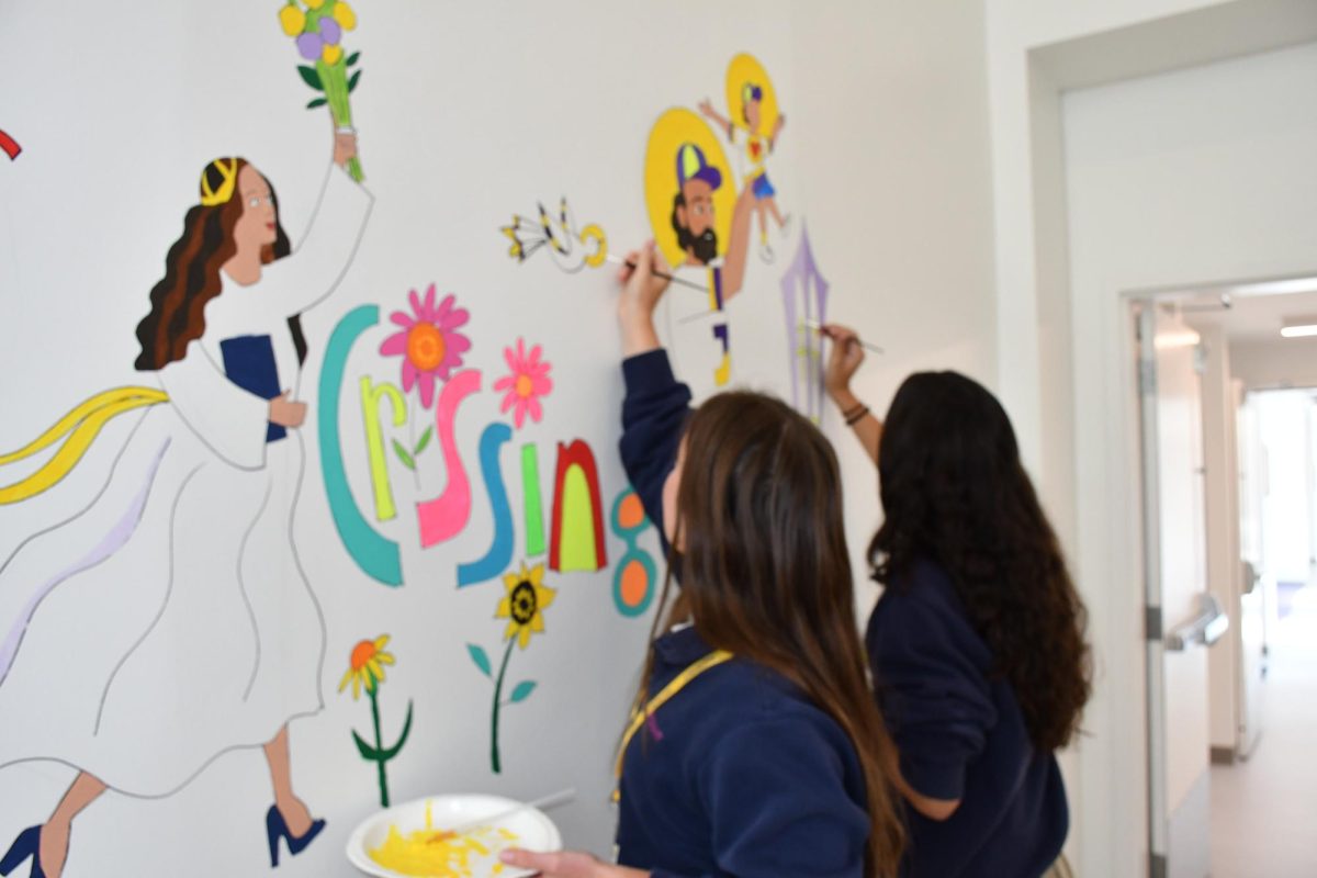 Molly Giordano '27 and Leah Hartzel '27 add paint to the mural during Theology class. 