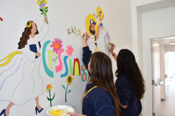 Molly Giordano '27 and Leah Hartzel '27 add paint to the mural during Theology class. 