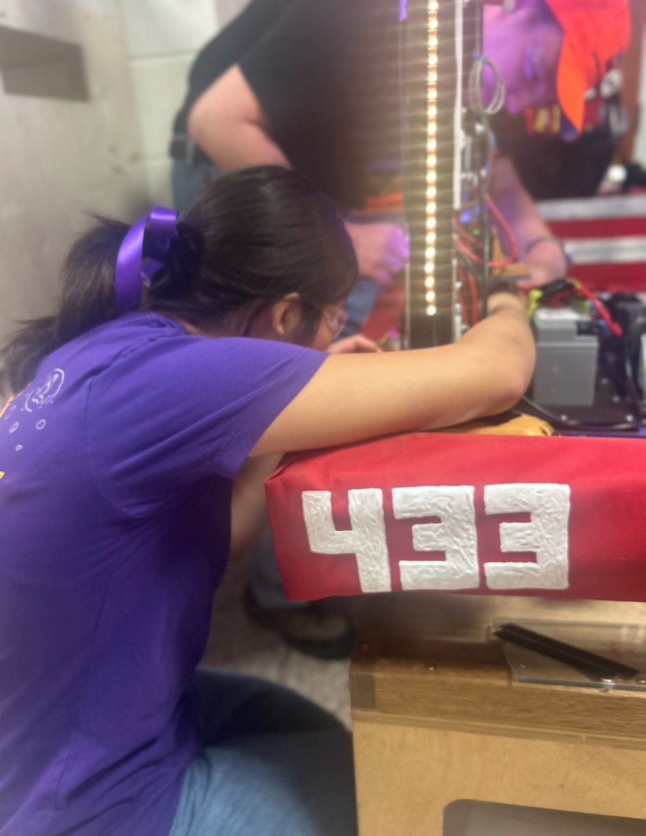 Co president and senior Emma Meng ‘26 adds the alternate red bumpers to the robot, emblazoned with the Firebirds’ number ‘433’. Emma worked in tandem with her co-president, other student members, and staff leaders to ensure the success of their robot, which was built during the off season.

 “Since freshman year, GirlPOWER has been a staple in my high school experience” Meng said. “In fact, my first ever GirlPOWER was my first instance of seeing real robots: a moment that sealed my loyalty towards the robotics program. This year, I was extremely grateful to take on a larger leadership role within such an influential event. From designing promotional materials to working alongside my team members to build the field, I was able to get to know my teammates more intimately, and start to find my rhythm with my co-leaders. Most of all, it was extremely fulfilling to see the changes and decisions we made benefit the overall event. On the day of GirlPOWER, watching girls get the opportunity to take lead, I felt as though all my efforts came to fruition.”
