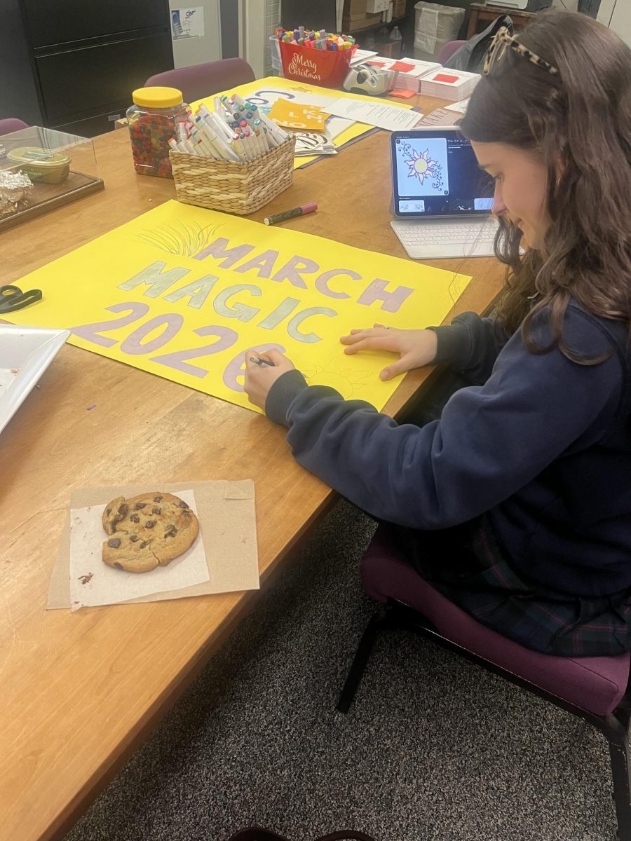 Fiona Corr ‘27 creates poster for March Magic Happy Hour while snacking on the beloved Mount cookie. 